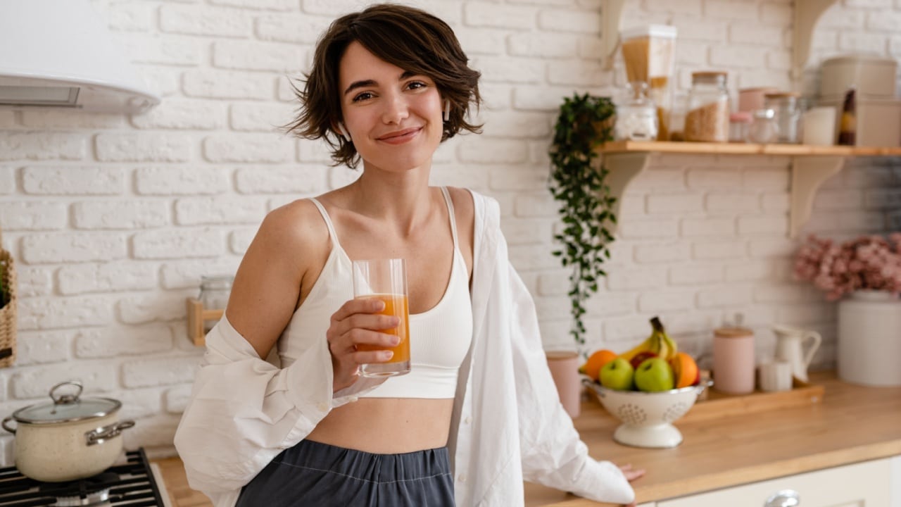 healthy woman in kitchen drinking juice.