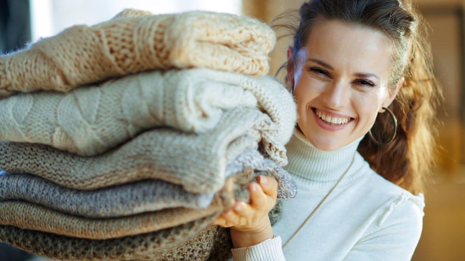 happy woman smiling organizing clothes blankets.