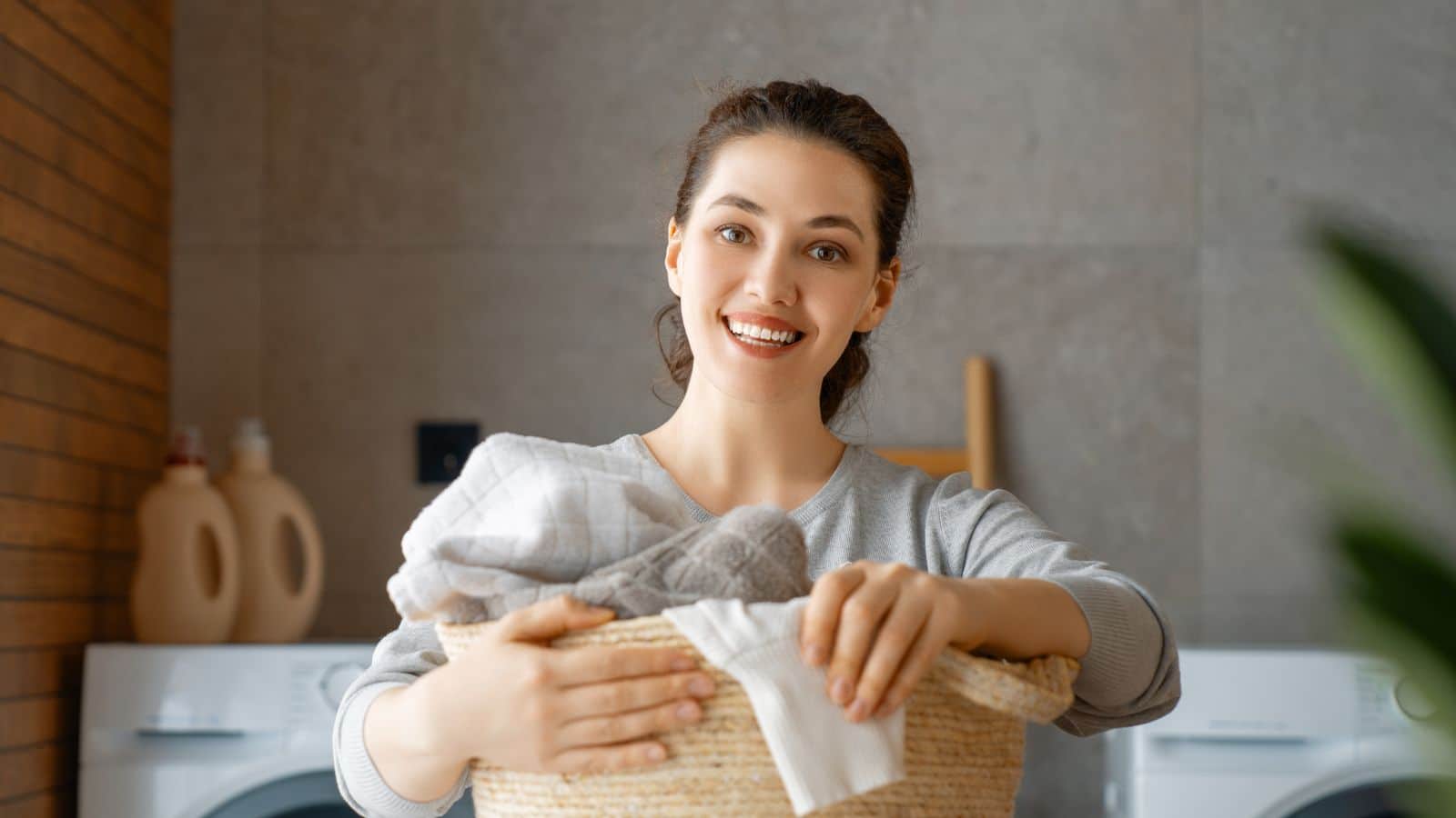 woman carrying basket of laundry clothes smiling